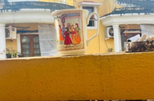Yellow balcony with a coffee mug on the railing, symbolizing a quiet moment of connection with the woman across the balcony.