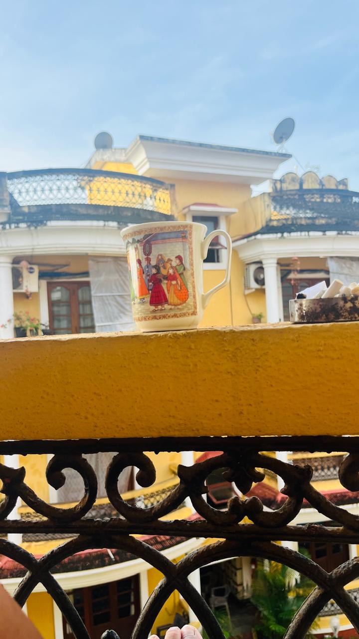 Yellow balcony with a coffee mug on the railing, symbolizing a quiet moment of connection with the woman across the balcony.
